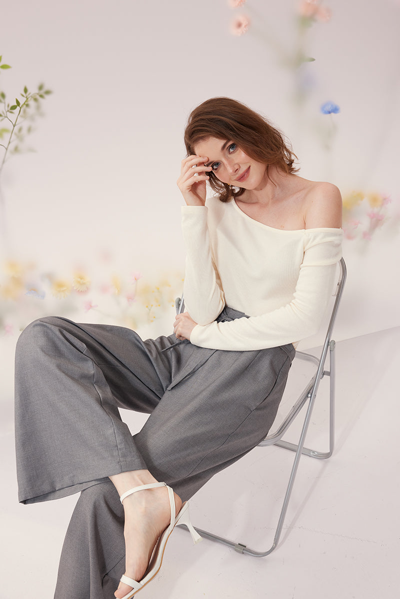 Polera marfil de escote asimétrico con pantalón gris de pierna ancha